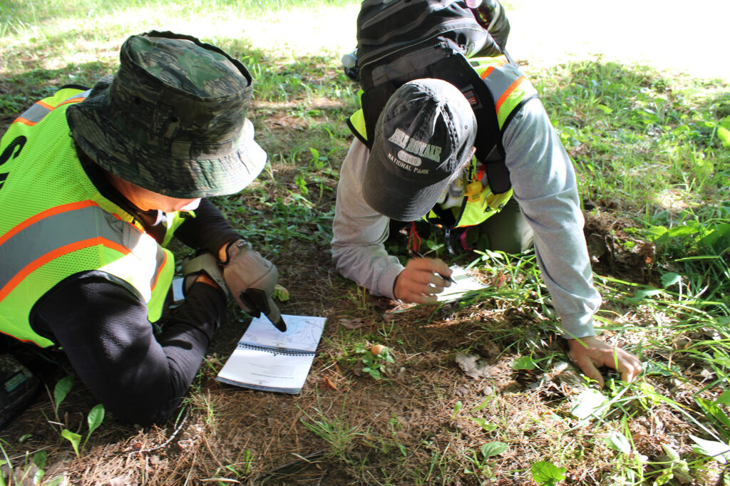 Two students taking notes on a track during a SAR tracking course.