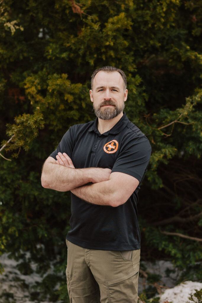 Profile photo of Vargold Instructor Patrick Diedrich in a black short sleeve polo with a Search and Rescue logo.