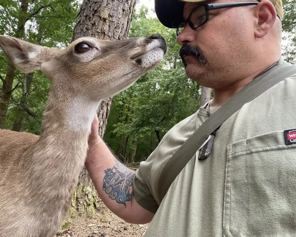 Photo of Kenny Brunswig, owner of Grumpy Bushcraft, staring down a white-tailed deer.