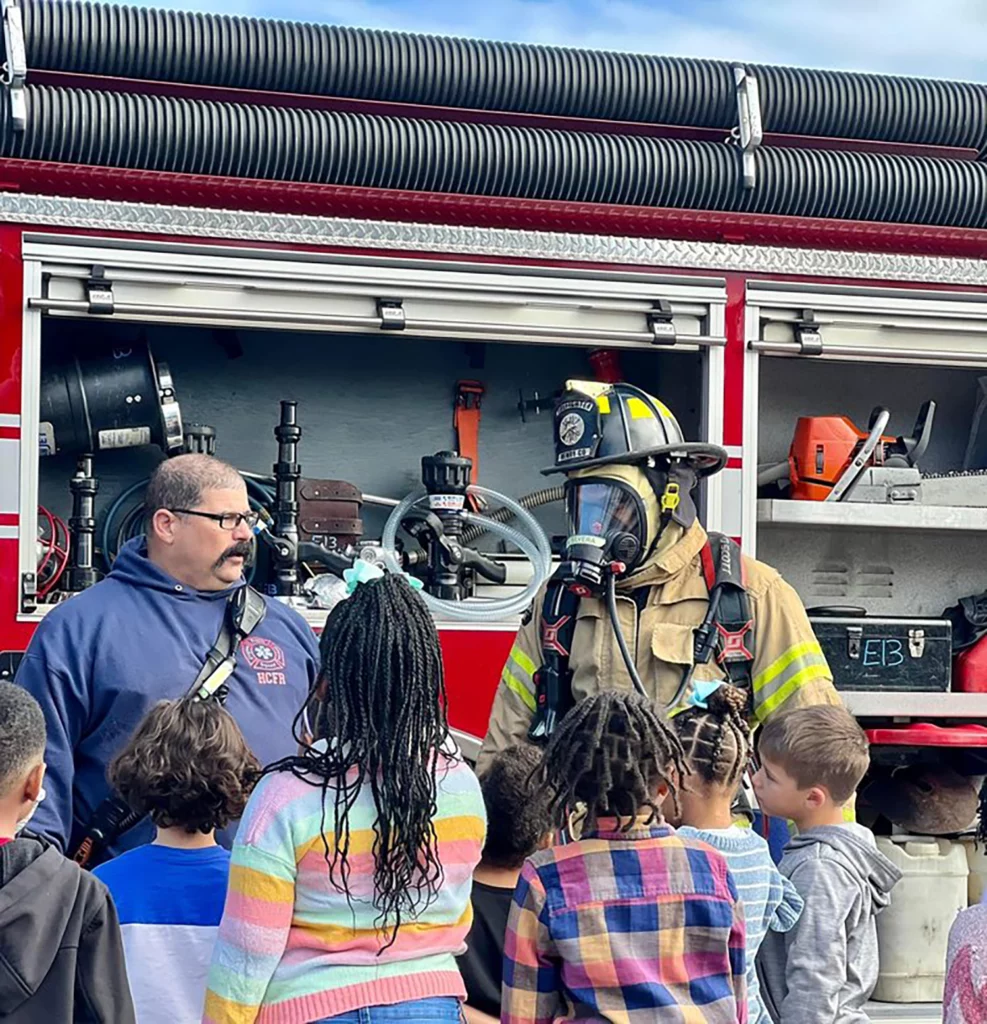 Photo of Kenny Brunswig teaching a group of children about fire safety.