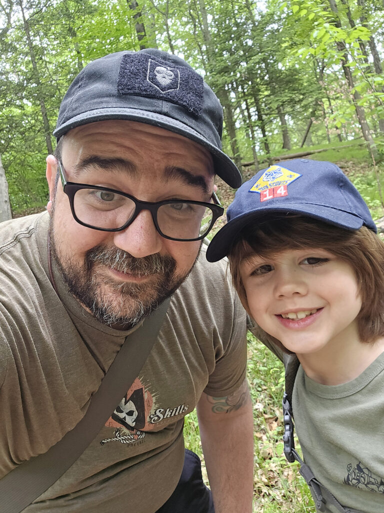 Nick Italiano in a green forest with one of his children.