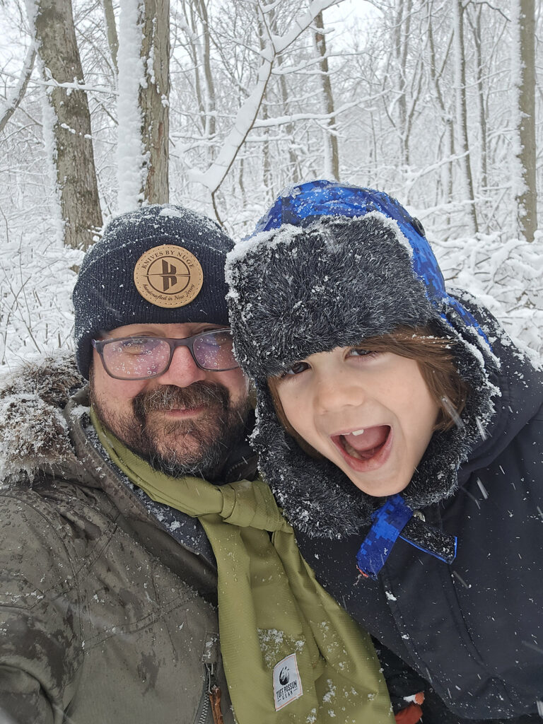 Nick in a snowy forest with on of his children.